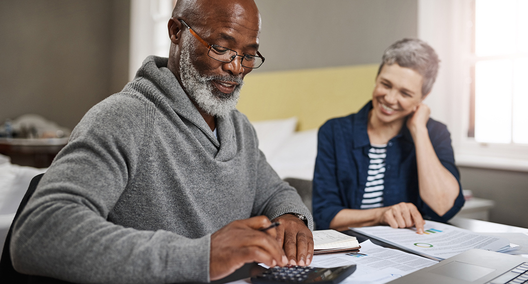 Retired man calculating his Medicare costs with an elderly female advising him
